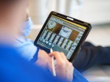 Zahnarzt betrachtet Röntgenbilder auf Tablet während Behandlung