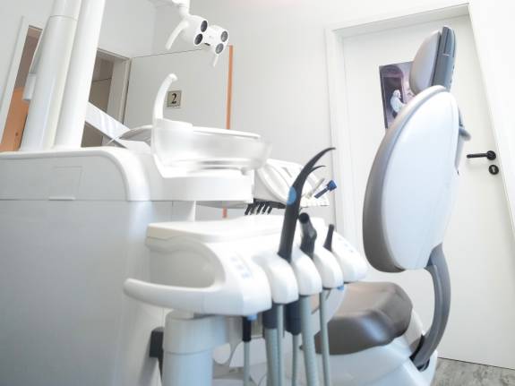 Moderner Behandlungsraum mit Zahnarztstuhl und Deckenbild.