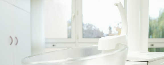 Helles Behandlungsbecken vor Fenster in moderner Zahnarztpraxis.