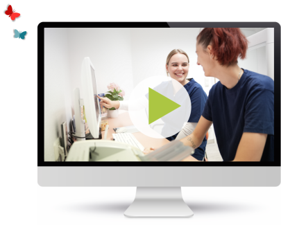 Zwei Mitarbeiterinnen arbeiten am Computer, Video-Play-Symbol im Vordergrund.