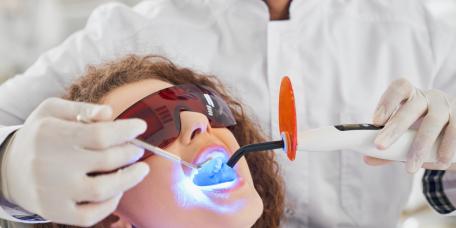 Patientin erhält Zahnbehandlung mit UV-Licht und Schutzbrille.