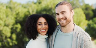 Glückliches Paar lächelt gemeinsam in die Kamera im Freien.